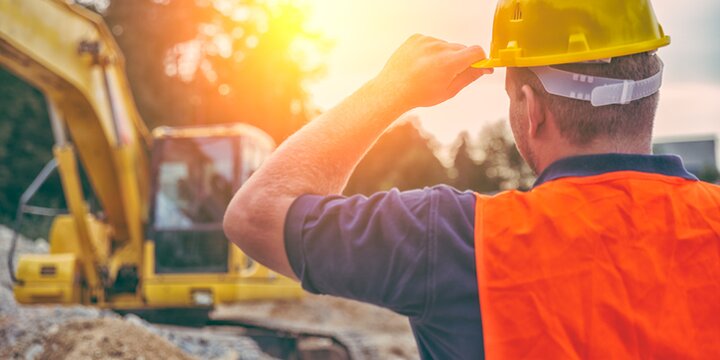 Berufserfahrung | © iStock/GregorBister Baggerführer mit Helm mit dem Rücken vor seinem Bagger | © iStock/GregorBister